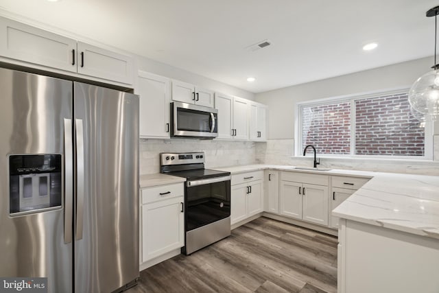 kitchen with pendant lighting, white cabinetry, sink, and stainless steel appliances