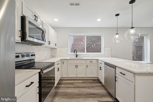 kitchen with light stone counters, white cabinetry, and appliances with stainless steel finishes