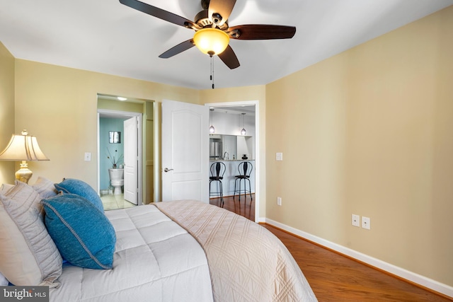 bedroom with a ceiling fan, baseboards, wood finished floors, and ensuite bathroom