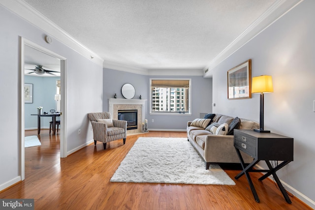 living room featuring ornamental molding, a fireplace, a textured ceiling, and wood finished floors