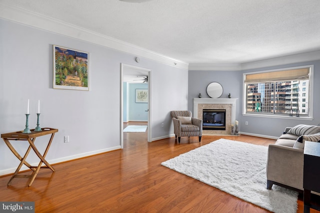 living room with a textured ceiling, a fireplace, wood finished floors, and baseboards