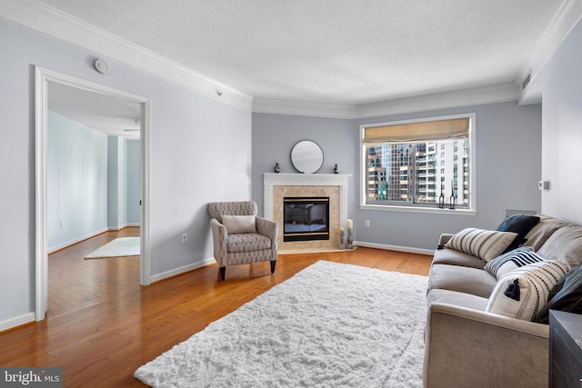 living room featuring a textured ceiling, wood finished floors, a high end fireplace, baseboards, and crown molding