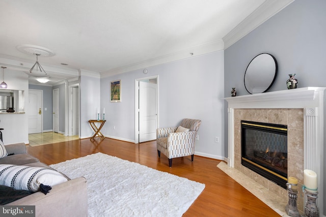 living area with ornamental molding, a high end fireplace, baseboards, and wood finished floors