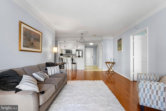 living area with light wood-style floors, baseboards, and crown molding