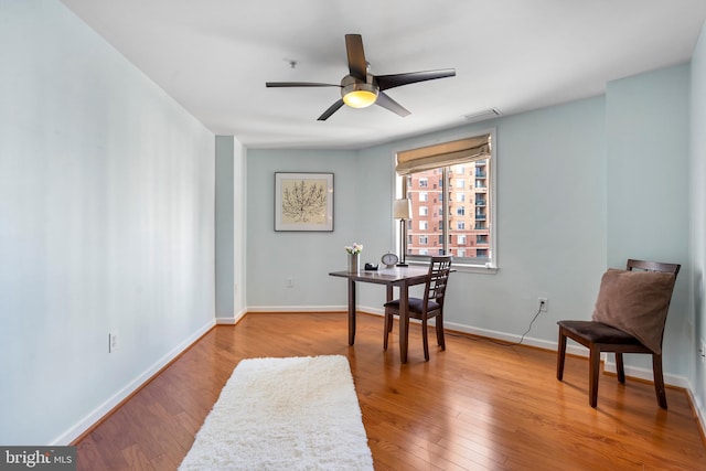 office with a ceiling fan, visible vents, baseboards, and hardwood / wood-style flooring