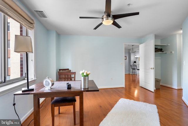 home office featuring a wealth of natural light, visible vents, baseboards, and wood finished floors