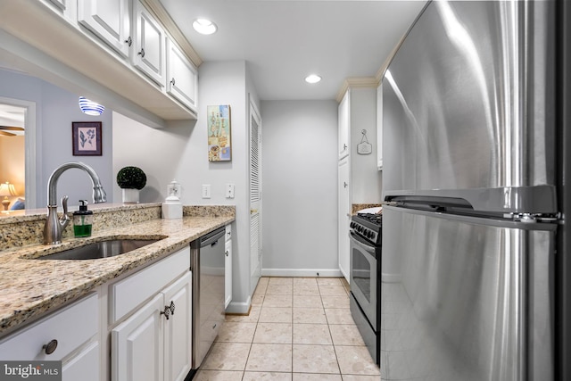 kitchen featuring light tile patterned floors, appliances with stainless steel finishes, a sink, and white cabinets