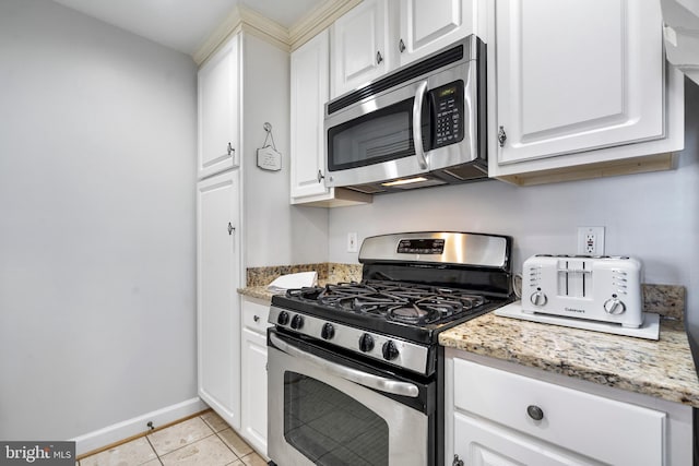 kitchen featuring appliances with stainless steel finishes, light tile patterned flooring, and white cabinetry