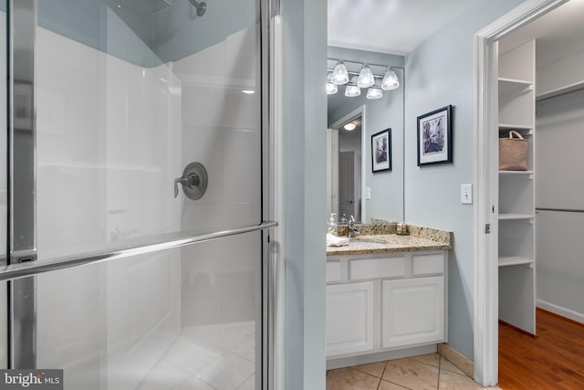 full bath featuring baseboards, a shower stall, vanity, and tile patterned floors