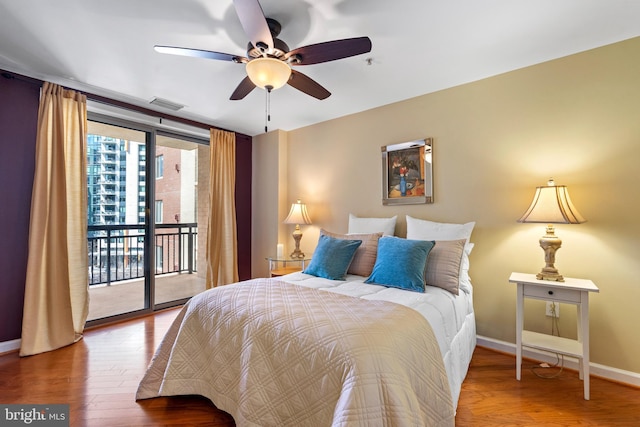 bedroom with baseboards, wood finished floors, visible vents, and access to exterior