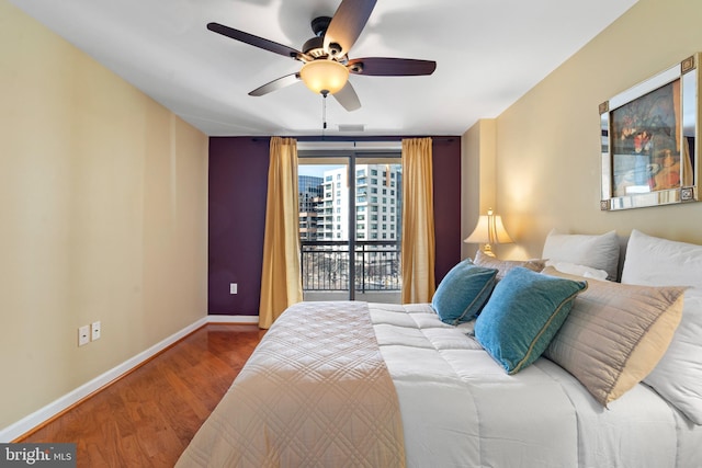 bedroom featuring access to exterior, a ceiling fan, baseboards, and wood finished floors