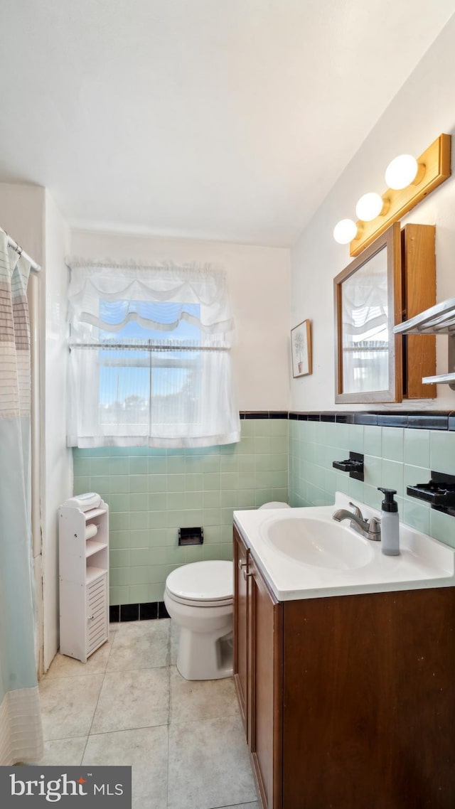 bathroom featuring tile patterned flooring, vanity, tile walls, and toilet