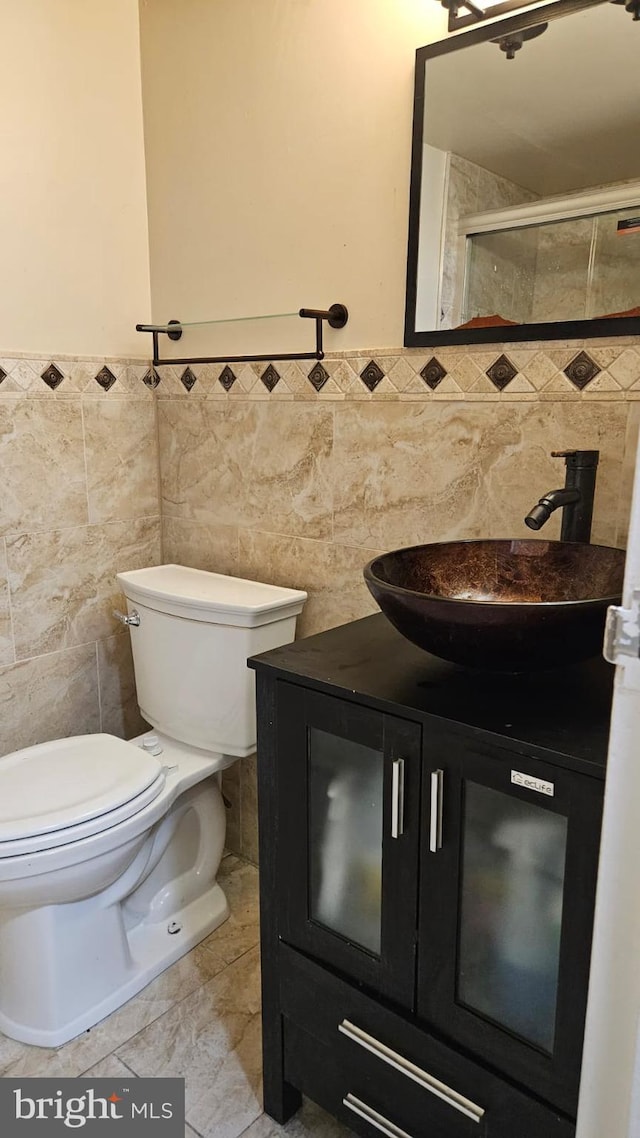 bathroom featuring tiled shower, vanity, toilet, and tile walls