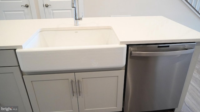 interior details with stainless steel dishwasher, gray cabinetry, and sink