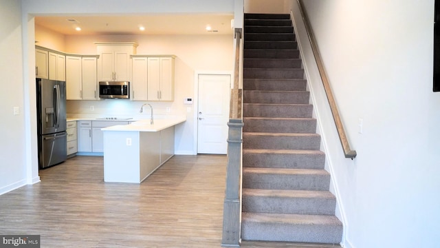 kitchen featuring white cabinets, light hardwood / wood-style floors, sink, and appliances with stainless steel finishes