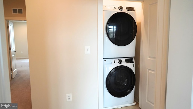 laundry area with stacked washer and dryer and light colored carpet