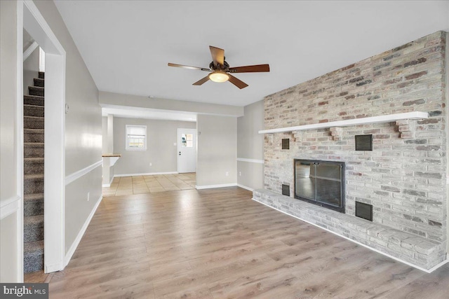 unfurnished living room featuring a brick fireplace, ceiling fan, and wood-type flooring