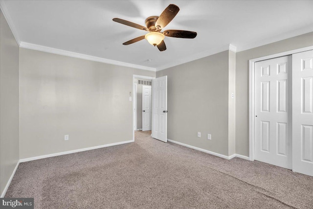 unfurnished bedroom featuring ornamental molding, carpet floors, ceiling fan, and a closet