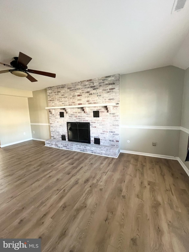 unfurnished living room with a large fireplace, ceiling fan, lofted ceiling, and hardwood / wood-style flooring