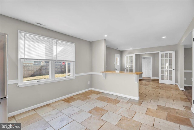 kitchen featuring kitchen peninsula, french doors, and a kitchen breakfast bar