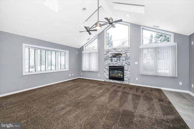 unfurnished living room with carpet, ceiling fan, a large fireplace, and a wealth of natural light