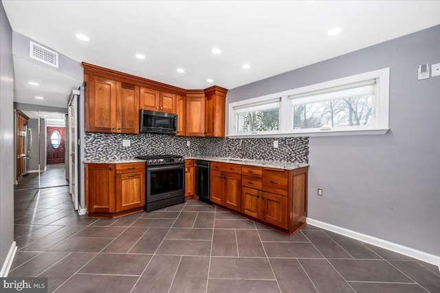 kitchen featuring decorative backsplash, dark tile patterned floors, light stone counters, black dishwasher, and stainless steel range oven