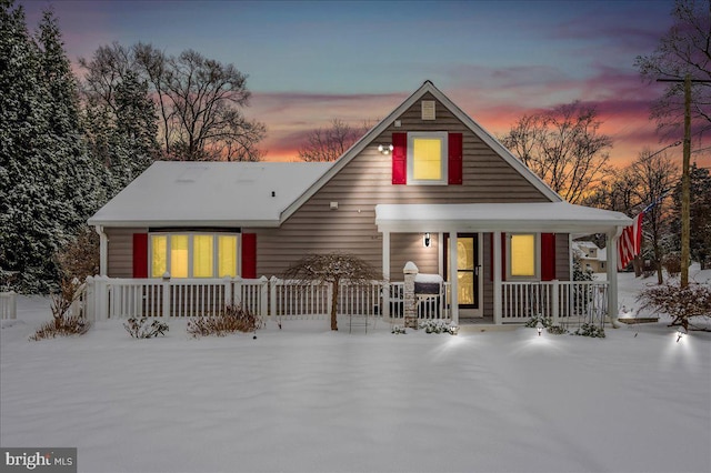 snow covered back of property featuring a porch