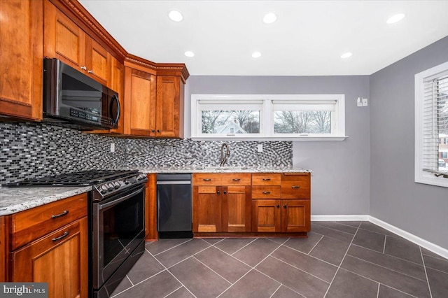 kitchen featuring sink, stainless steel appliances, light stone counters, dark tile patterned floors, and backsplash