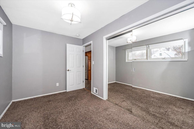 unfurnished bedroom with a closet and dark colored carpet