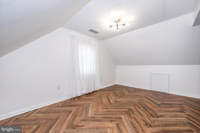 additional living space featuring dark parquet flooring and lofted ceiling