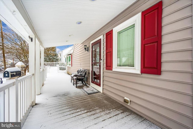 snow covered deck with area for grilling and a porch