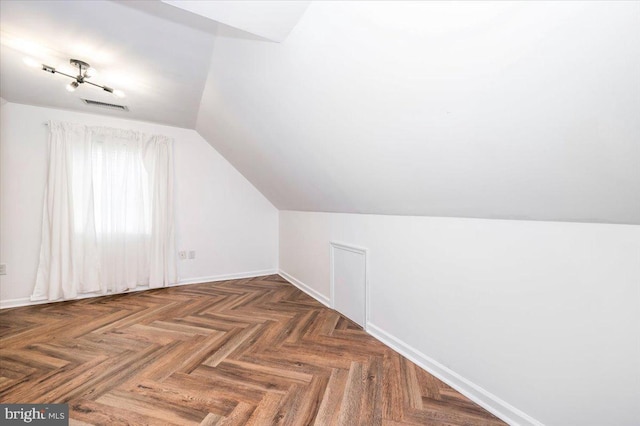 bonus room featuring dark parquet flooring and vaulted ceiling