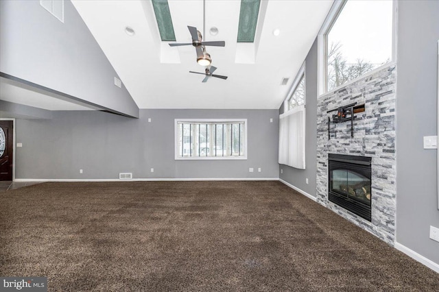 unfurnished living room with a skylight, ceiling fan, high vaulted ceiling, carpet floors, and a fireplace