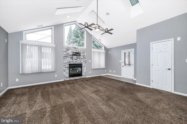 unfurnished living room featuring ceiling fan, a fireplace, high vaulted ceiling, and a skylight