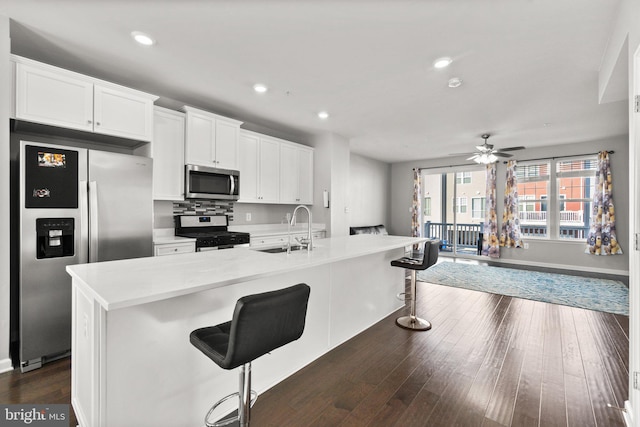 kitchen featuring stainless steel appliances, a kitchen island with sink, sink, and a breakfast bar