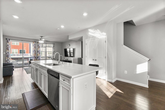 kitchen featuring dark wood-type flooring, a center island with sink, dishwasher, and sink