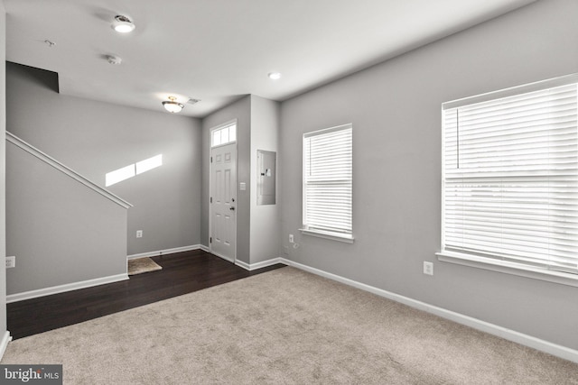 foyer featuring electric panel and dark colored carpet