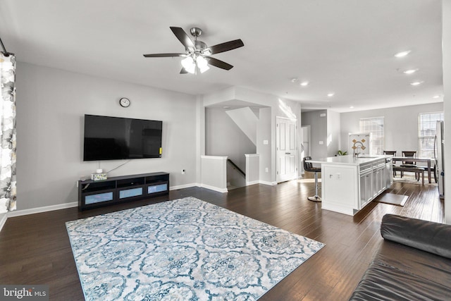 living room featuring sink, dark wood-type flooring, and ceiling fan