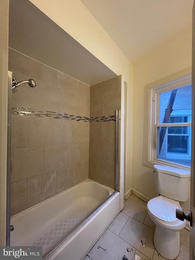 bathroom with tile patterned floors, bath / shower combo with glass door, and toilet