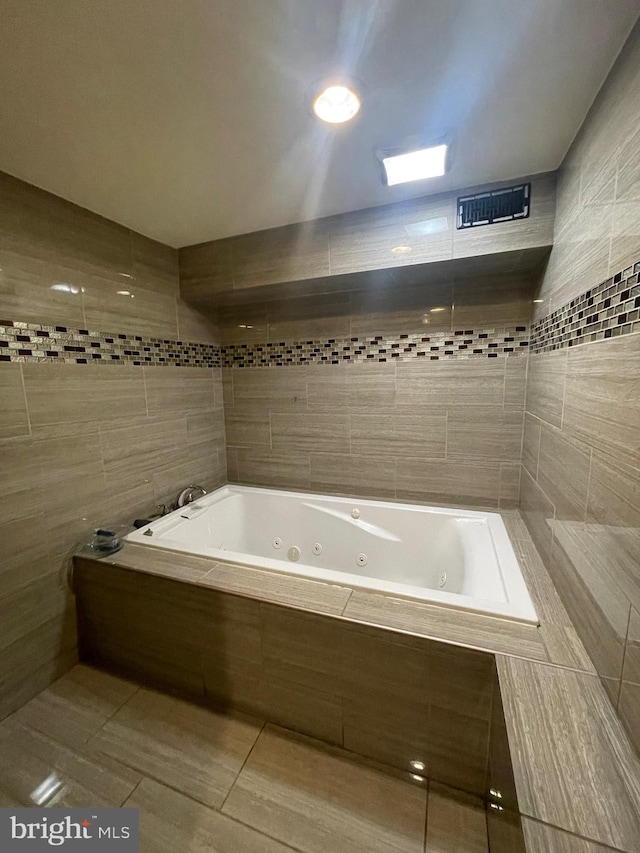 bathroom with tile patterned floors, tiled tub, and tile walls