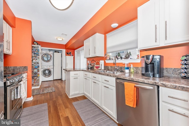 kitchen featuring stacked washing maching and dryer, sink, white cabinets, light hardwood / wood-style floors, and stainless steel appliances