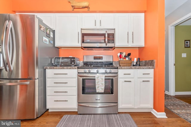 kitchen with white cabinetry, hardwood / wood-style flooring, and appliances with stainless steel finishes