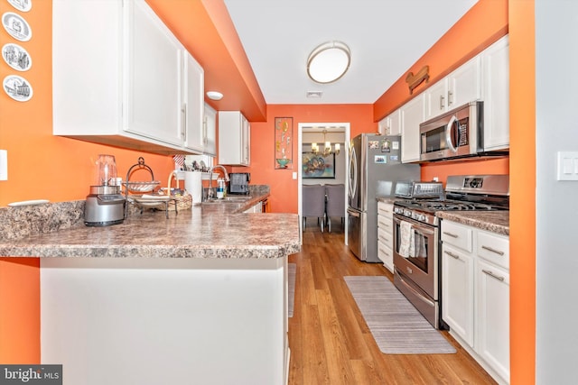 kitchen featuring sink, appliances with stainless steel finishes, kitchen peninsula, light hardwood / wood-style floors, and white cabinets