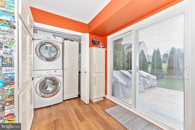 clothes washing area featuring stacked washer / drying machine and light hardwood / wood-style flooring