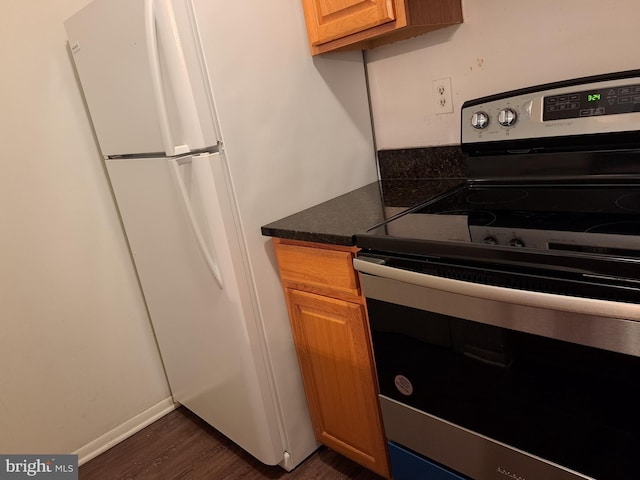 kitchen featuring dark hardwood / wood-style flooring, white fridge, and stainless steel electric stove