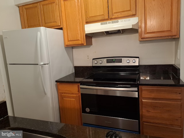 kitchen with electric stove, dark stone counters, and white refrigerator