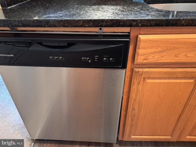 interior details with stainless steel dishwasher, dark stone countertops, and sink