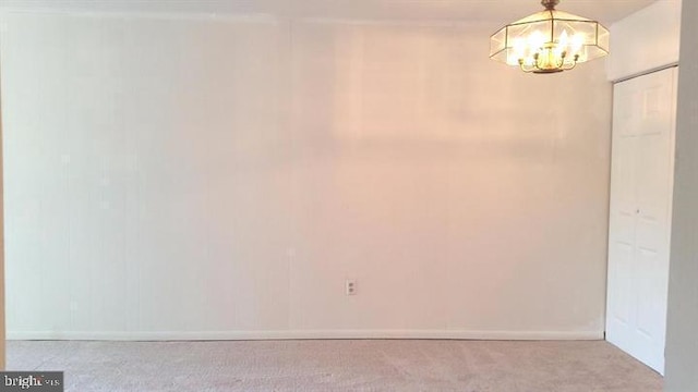 carpeted spare room featuring a chandelier