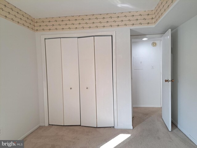 unfurnished bedroom featuring light carpet and a closet