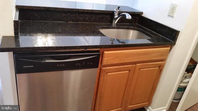 kitchen featuring dishwasher, sink, and dark stone counters